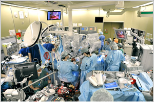 ダヴィンチによる手術の模様。患者の側で助手がロボットアームに取り付ける手術器具の交換などを行う。術者は写っていないが、写真の手前にいる。患者から離れて、ケーブルでつながった操作台で遠隔操作する